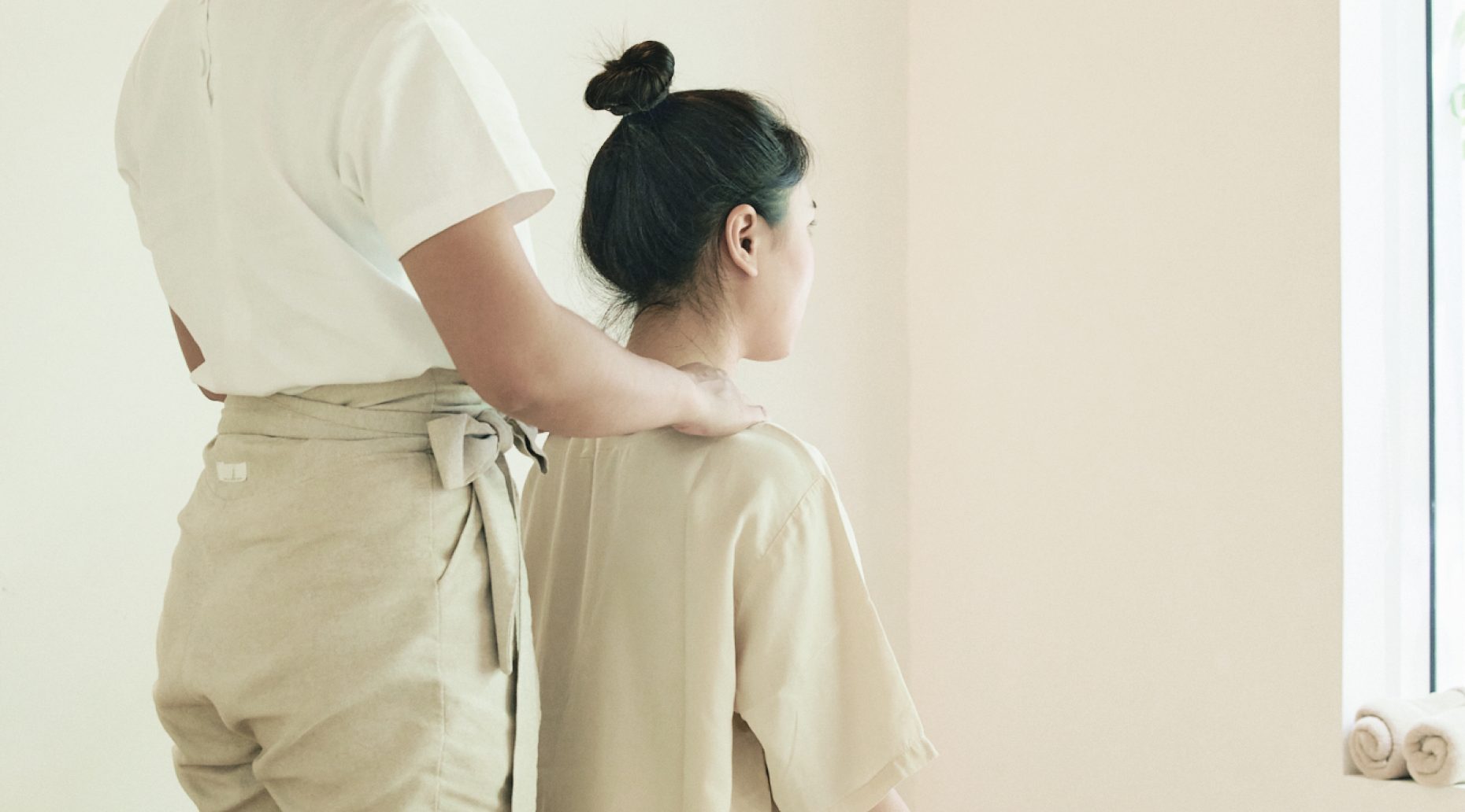 A therapist giving a client a neck massage at White Wood Green boutique spa in Thonglor